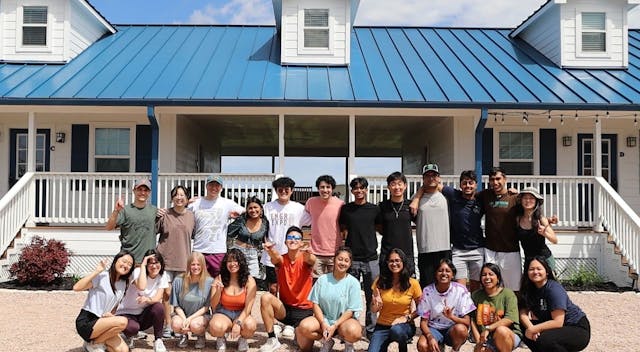 Group photo of IEEE members in front of a modern ranch house for a retreat