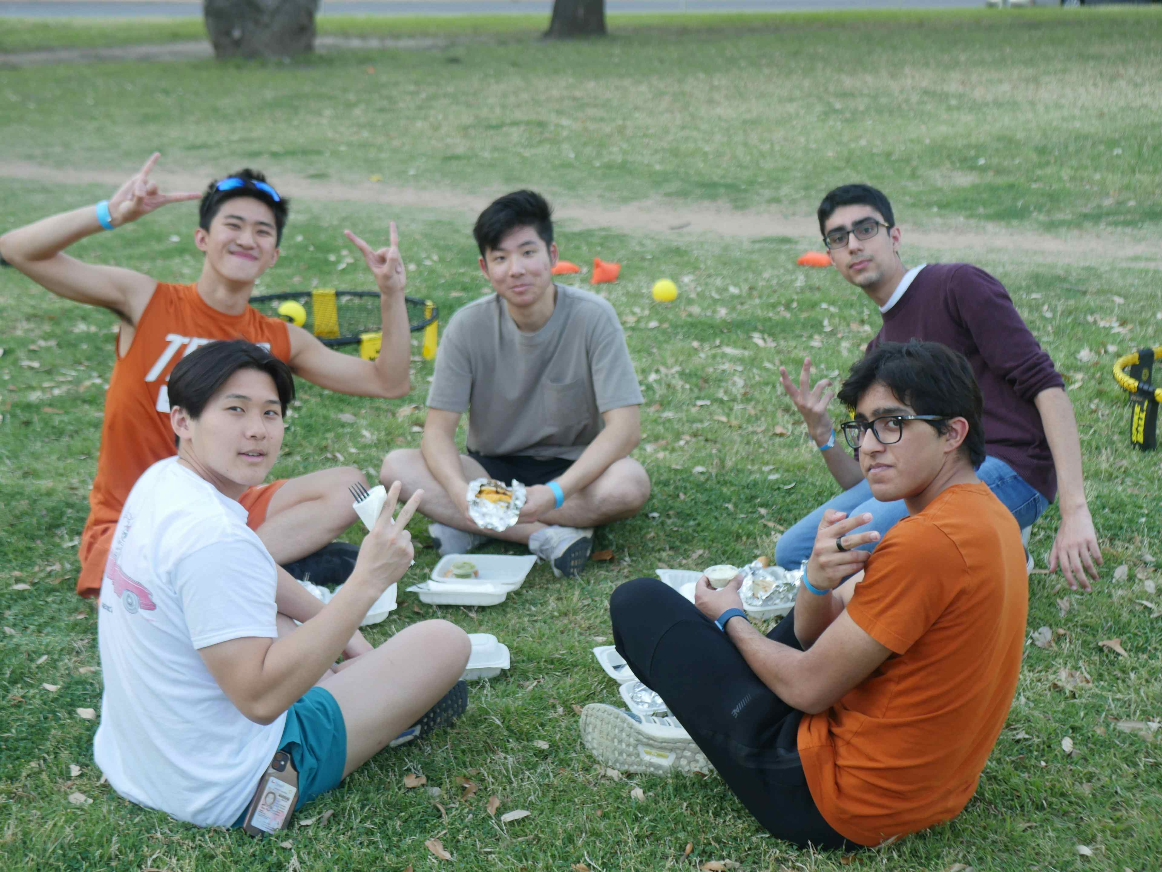 Members sit in circle on lawn smiling at the camera